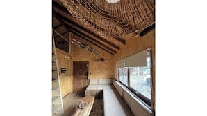 Un intérieur chaleureux avec un banc en bois, une fenêtre offrant une belle vue et un plafond rustique.
