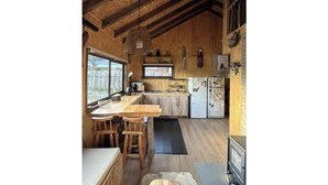 Une cuisine rustique avec des poutres en bois, un coin bar et un réfrigérateur décoré d’aimants.