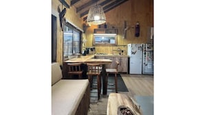 Une cuisine chaleureuse aux murs en bois, un coin repas avec un banc et un luminaire suspendu.