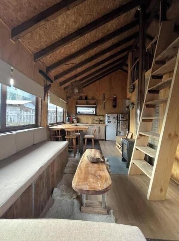 Un interior rústico con un banco de madera, una zona de cocina y un ventanal.