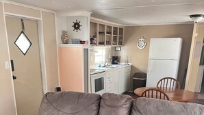 A living room with a grey sofa, a wooden dining table, and a kitchen area in the background. - Home Away From Home 2 (East Palatka)