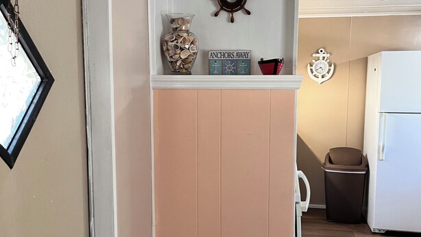 A kitchen with a white refrigerator, a trash bin, and a wooden floor. - Home Away From Home 2 (East Palatka)