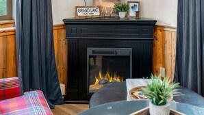 A cozy living room with a fireplace, plaid sofa, and a small table with a plant.
