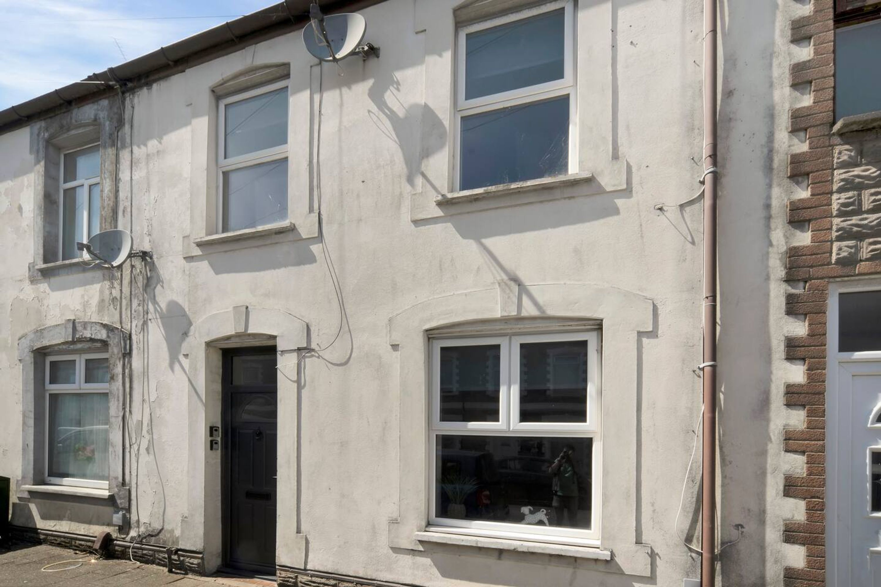 A two-story building with multiple windows, a satellite dish, and a door.