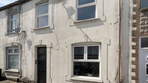 Een gebouw met twee verdiepingen, meerdere ramen, een schotelantenne en een deur.