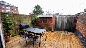 A wooden deck with a table and chairs, a barbecue grill, and a small wooden shed. - Beautiful Cardiff Wharf Free Parking Waterviews (Cardiff)