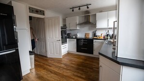 A modern kitchen with white cabinets, a black refrigerator, and wooden flooring. - Beautiful Cardiff Wharf Free Parking Waterviews (Cardiff)