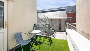 A small outdoor patio with a green lawn, a metal chair, a small table, and a staircase leading to a building. - Spacious Cardiff Central Fast Wifi Netflix (Cardiff)