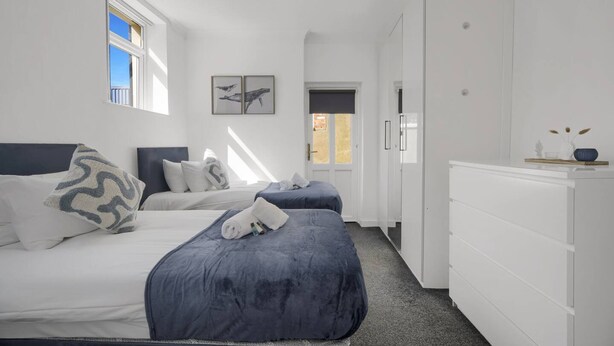 A bedroom with two beds, a dresser, and a window with artwork. - Spacious Cardiff Central Fast Wifi Netflix (Cardiff)