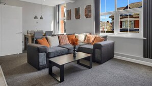 A modern living room with a grey sofa set, a coffee table, and a dining area with a table and chairs. - Spacious Cardiff Central Fast Wifi Netflix (Cardiff)