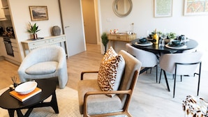 Ein modernes Wohnzimmer mit Essbereich, ausgestattet mit einer Couch, Sesseln, einem Couchtisch und einem Esstisch für sechs Personen.