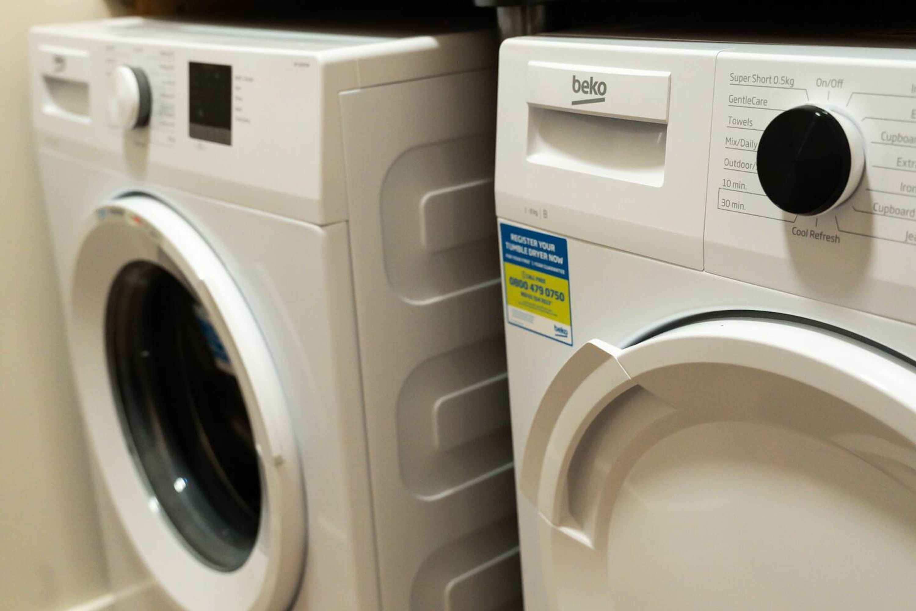 Two front-loading washing machines with control panels and a label.