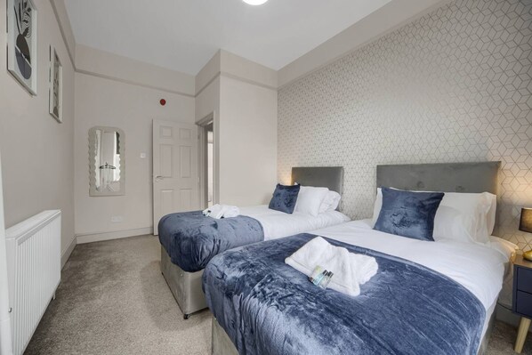 A hotel room with two beds, a radiator, a door, and a wall with a geometric pattern. - Free Parking Fast Wifi 2 Min to Cardiff City (Cardiff)