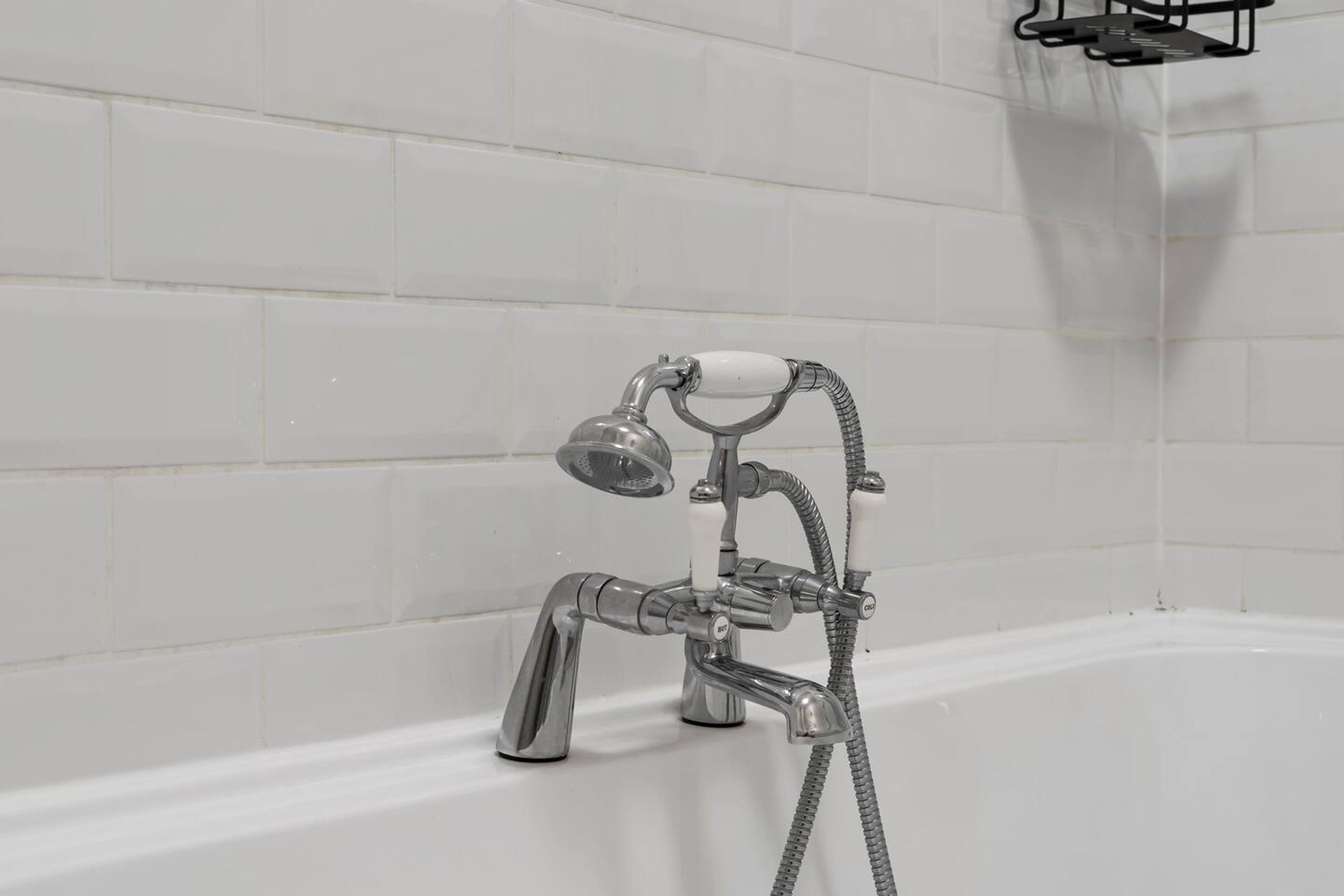 A modern bathroom with a bathtub, a handheld showerhead, and a wall-mounted faucet.