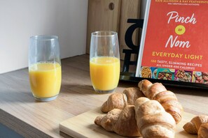 Two glasses of orange juice and a book titled 'Pinch of Nom Everyday Light' on a wooden surface. - Free Parking Fast Wifi 2 Min to Cardiff City (Cardiff)