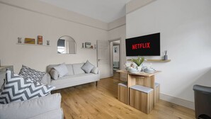A modern living room with a sofa, coffee table, and TV displaying 'NETFLIX'. - Free Parking Fast Wifi 2 Min to Cardiff City (Cardiff)