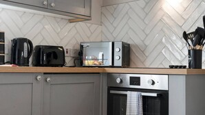A modern kitchen with a herringbone tile backsplash, a toaster, a kettle, and an oven. - Free Parking Fast Wifi 2 Min to Cardiff City (Cardiff)