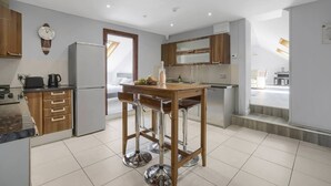 Una cocina moderna con armarios de madera, un refrigerador de acero inoxidable y un taburete de bar.