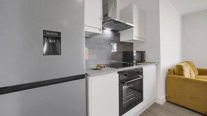 Une cuisine moderne équipée d’un distributeur d’eau, d’appareils électroménagers en acier inoxydable et d’un canapé jaune placé dans un coin.