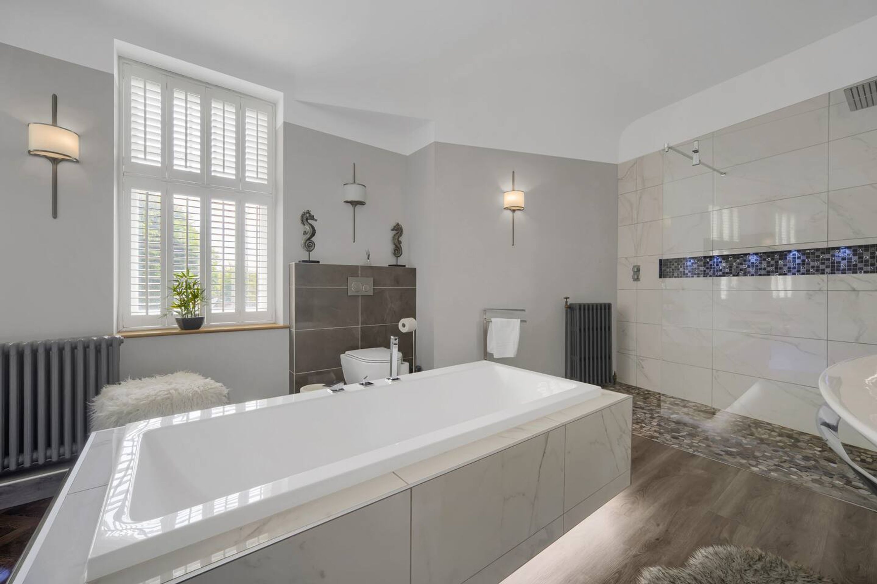 A modern bathroom with a large bathtub, a toilet, and a shower area.