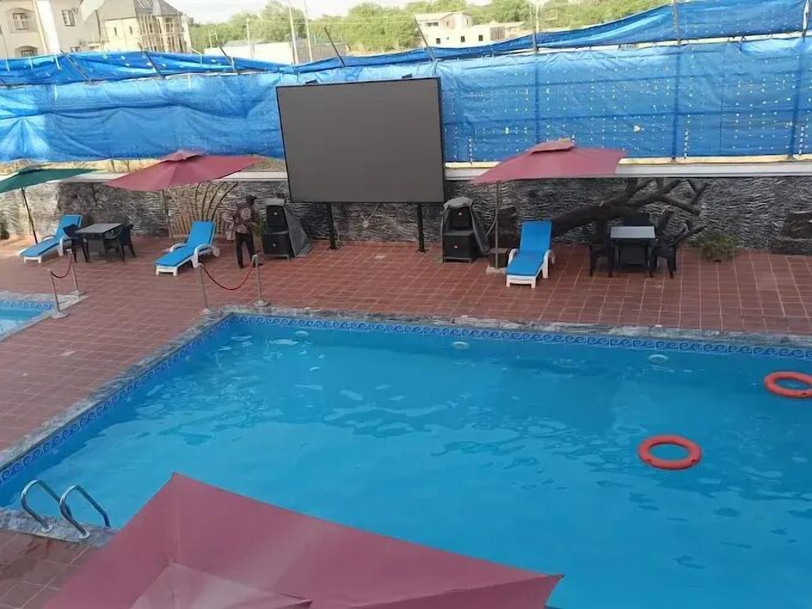 Ein Swimmingpool mit blauem Wasser, umgeben von Liegestühlen und Sonnenschirmen.