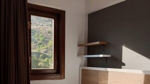 A hotel room with a bed, a window with curtains, a headboard, and a shelf unit. - SERGE HOTEL  (Arapgir)