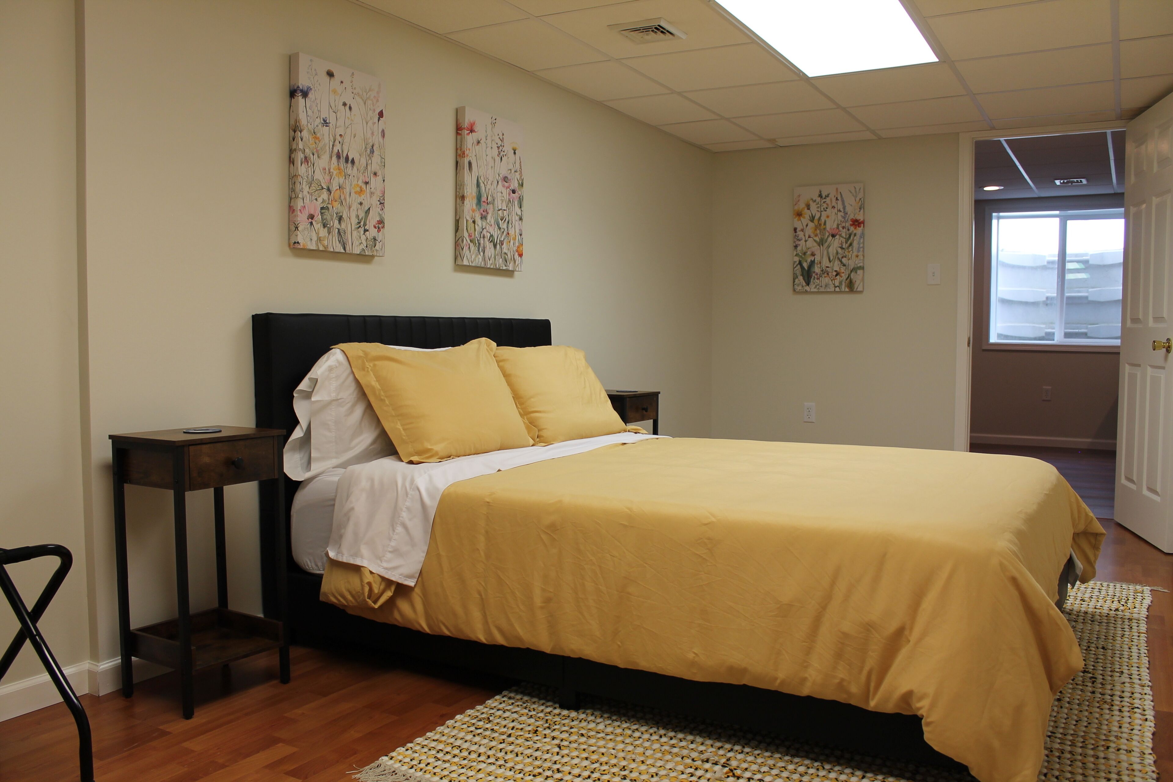 A bedroom with a bed, a nightstand, a chair, and artwork on the walls.