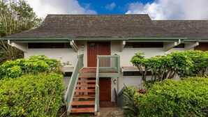 A two-story building with a wooden staircase leading to a front door. - Heavenly Kauai Destinations Hale Moi Side B by Hideaways Beach (Princeville)