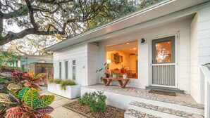 A white house with a front porch, a small garden, and a visible number '11' on the house.