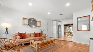 A modern living room with a sofa, coffee table, and a dining area with chairs.