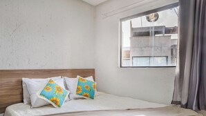 Ein Hotelzimmer mit einem Bett, zwei Kissen, einem Fenster und Blick nach draußen.