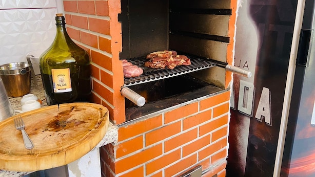 A brick-built outdoor oven with meat being cooked.