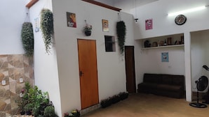 A room with a wooden door, potted plants, a clock, and a fan.