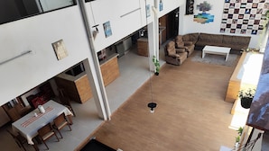 A spacious living area with a pool table, a sofa set, and a dining area with wooden furniture.