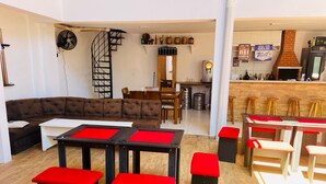 A modern living room with a sectional sofa, a dining area with red benches, and a kitchen area with a bar.