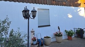 A traditional wooden building with a white exterior, large windows, and a small balcony with potted plants.