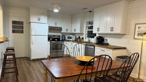 A kitchen with white cabinets, a wooden dining table, and a black floor lamp.