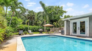 A swimming pool with a tiled edge, surrounded by a wooden deck and chairs. - Discover Your Ideal Retreat in Fort Lauderdale (Fort Lauderdale)