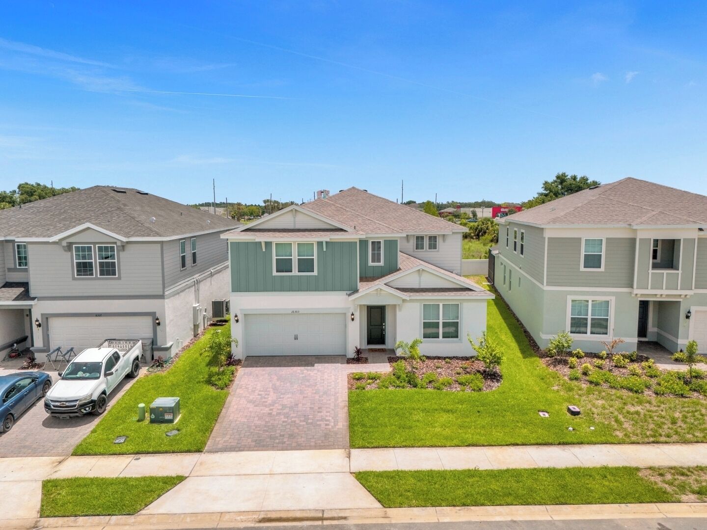 A row of townhouses with attached garages, a paved driveway, and a well-maintained lawn.
