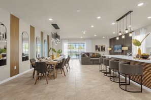 Una cocina moderna con zona de comedor, taburetes de bar y un ventanal amplio.