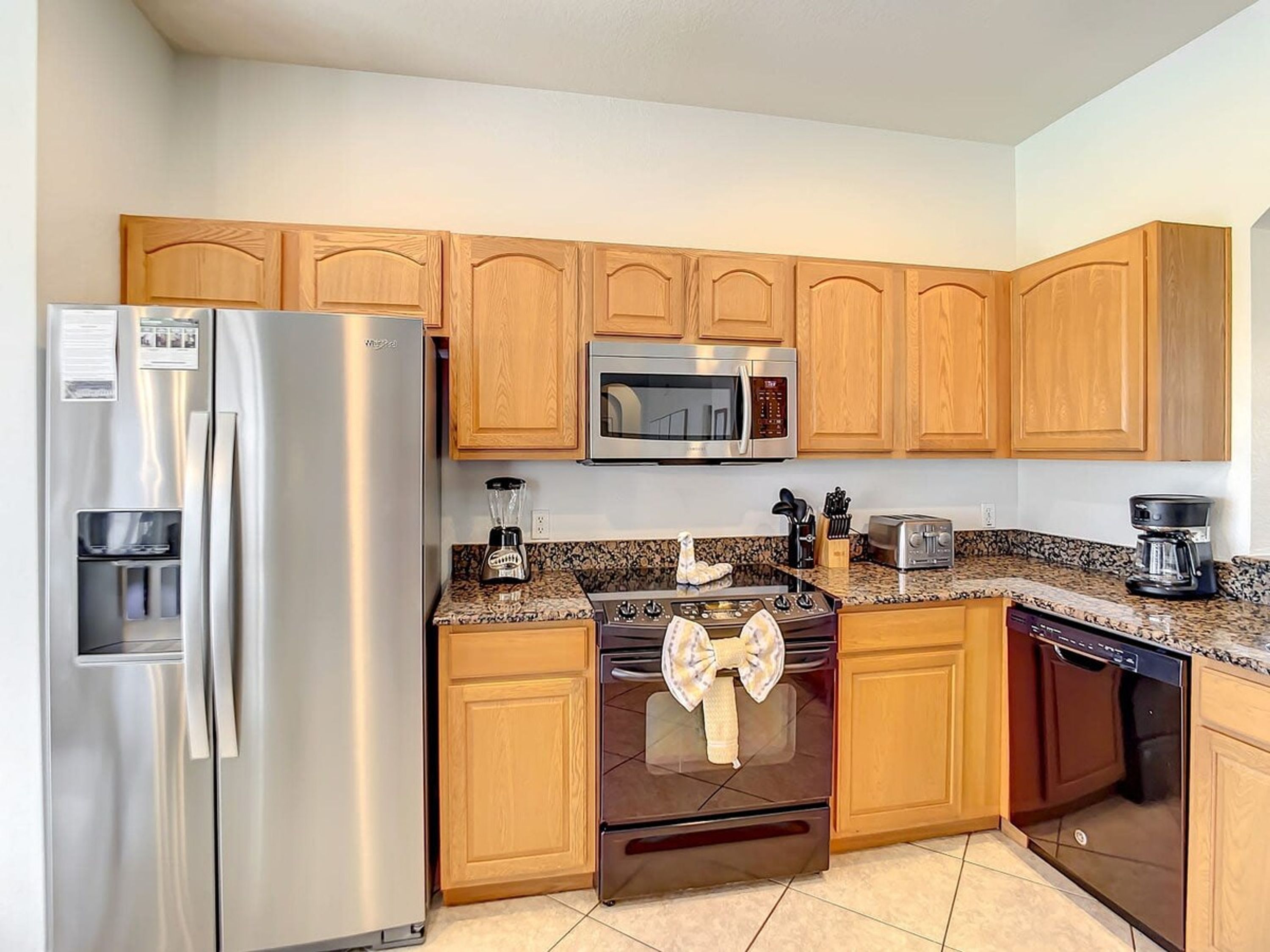 A kitchen with wooden cabinets, stainless steel appliances, a granite countertop, and a dishwash.