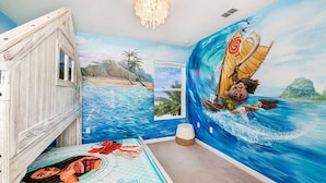 Une chambre avec une fresque représentant un paysage tropical marin, un cadre de lit en bois et une fenêtre donnant sur des palmiers.