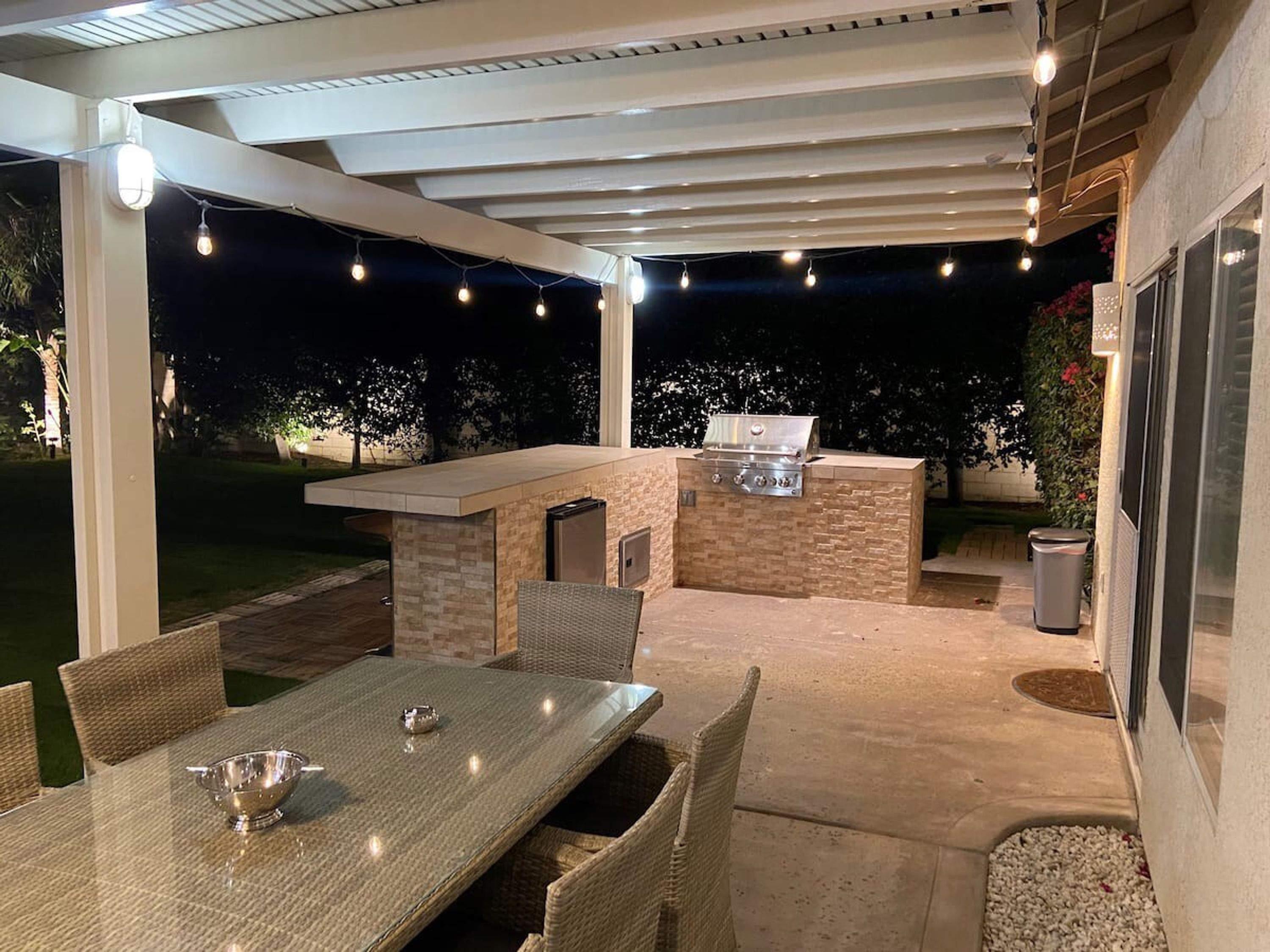 An outdoor patio with a grill, dining table, and chairs.