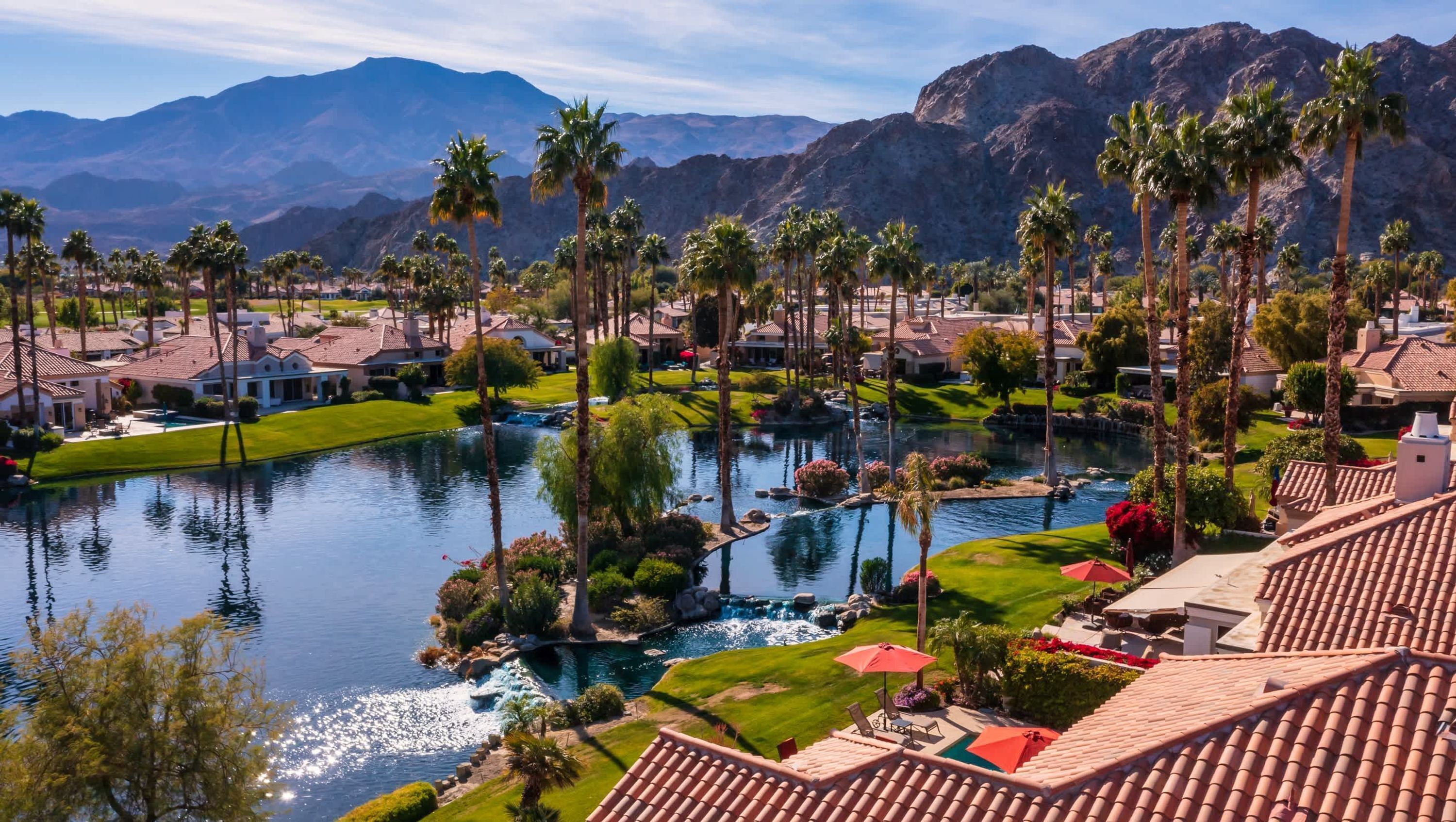 A resort with a large pool, palm trees, and mountain views.