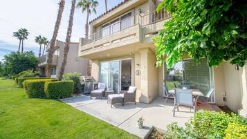 A two-story house with a patio, outdoor furniture, and a view of the neighborhood.