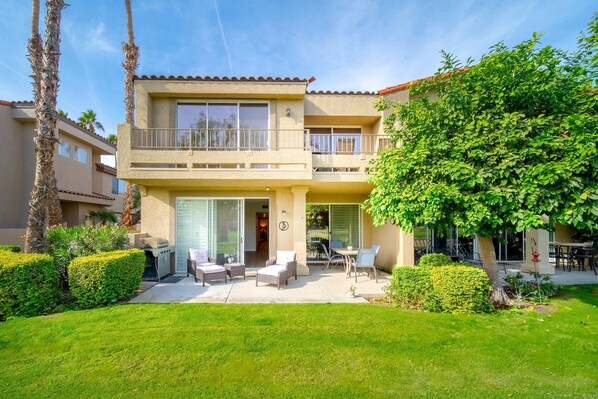 Un immeuble résidentiel de deux étages doté d’un balcon, d’un espace extérieur aménagé pour s’asseoir et d’une pelouse bien entretenue.