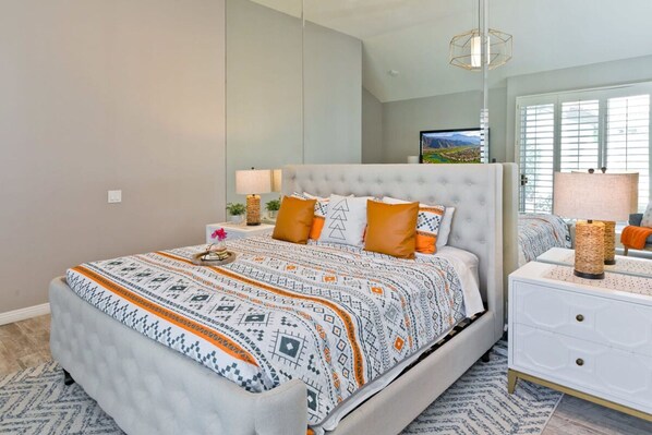 A bedroom with a large bed, a nightstand, a lamp, and a mirror. - Casa Havana Stunning Views Pool Spa PGA West 4br (La Quinta)