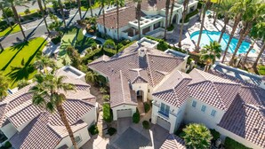 A residential area with multiple houses featuring terracotta roofs, palm trees, and a swimming pool.
