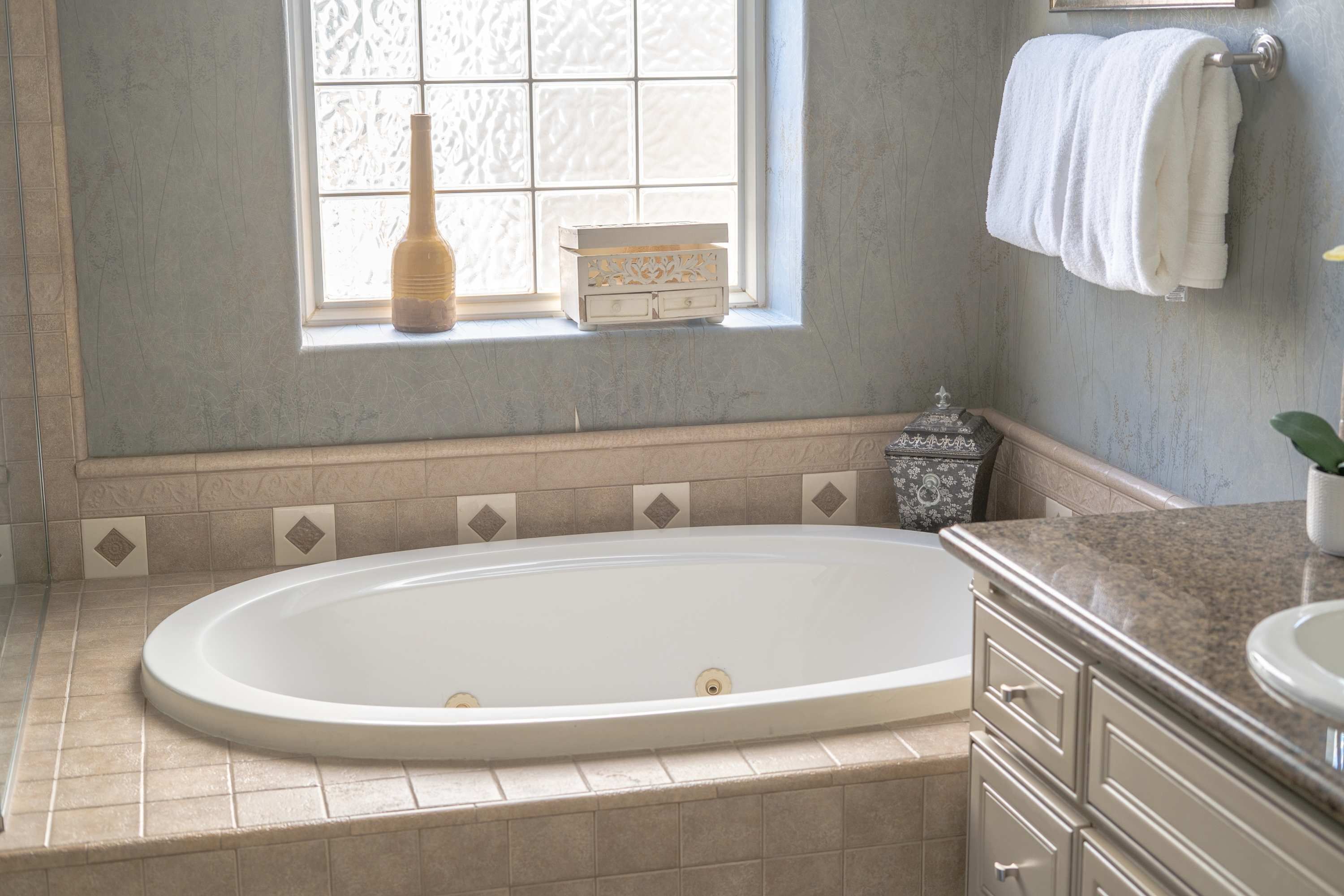A bathroom with a freestanding bathtub, a window with patterned glass, and a towel rack.