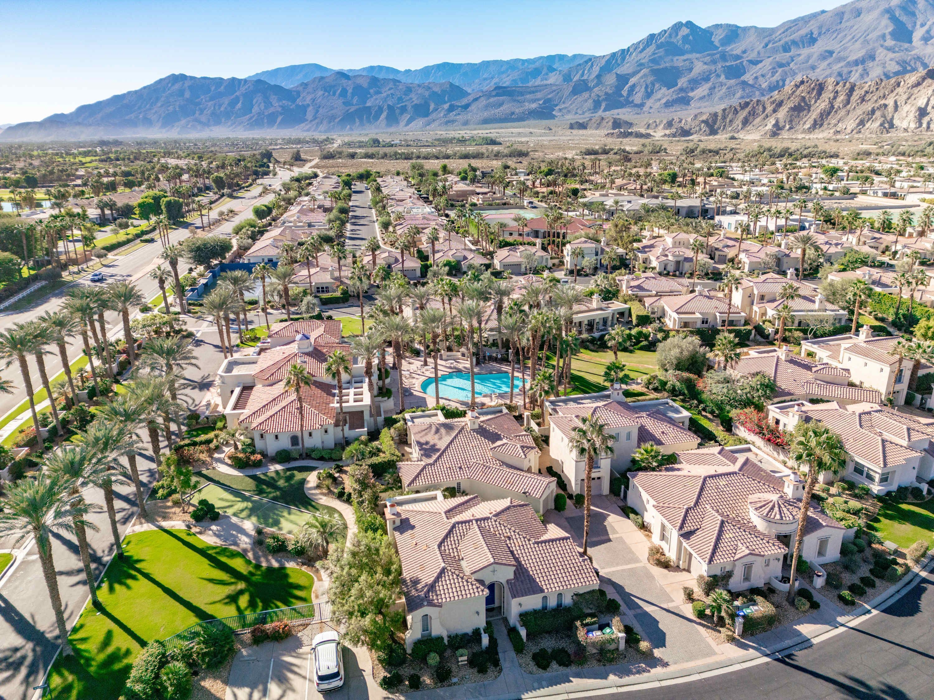 A residential area with houses, a swimming pool, and mountains in the background.